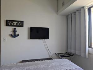 1 dormitorio con 1 cama y TV en la pared en Apartamento Ibiza Vista Mar, en Maceió