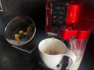 a cup of coffee is being poured into a coffee maker at Apartament ARKANA PREMIUM in Świętochłowice