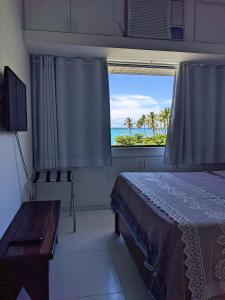a bedroom with a bed and a view of the ocean at Apartamento Ibiza Vista Mar in Maceió