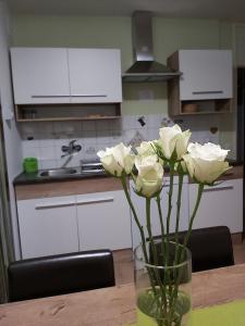 a vase with white roses on a table in a kitchen at apartma MAKS - Kobarid in Podbela