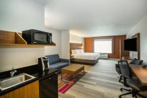 a hotel room with a bed and a living room at Holiday Inn Express Hotel & Suites Bellevue-Omaha Area, an IHG Hotel in Bellevue