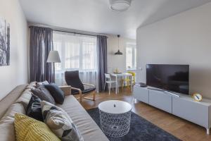 ein Wohnzimmer mit einem Sofa und einem Flachbild-TV in der Unterkunft Sun City Apartment in Šiauliai