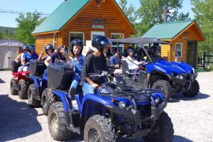 a group of people riding on atvs in front of a cabin at Auberge La Tanière in Tadoussac