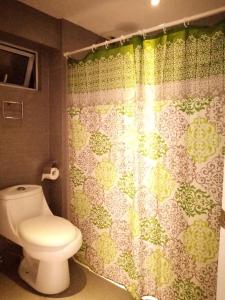 a bathroom with a toilet and a shower curtain at BGC Fort Victoria in Manila
