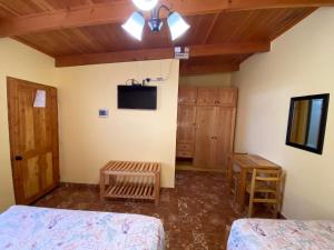 a bedroom with two beds and a tv and wooden ceilings at Las Cornizas de Catarpe in San Pedro de Atacama