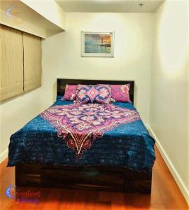 Un dormitorio con una cama con una manta de colores. en BGC Fort Victoria en Manila