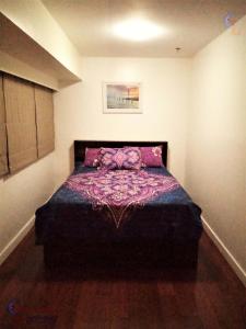 a bedroom with a bed with a purple blanket on it at BGC Fort Victoria in Manila