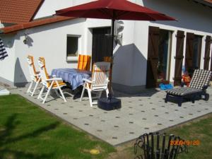un patio con mesa, sillas y sombrilla en Das Müritz Haus en Rechlin