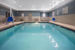 a large swimming pool with blue chairs in a building at Holiday Inn Express & Suites Sioux City North - Event Center by IHG in Dakota Dunes