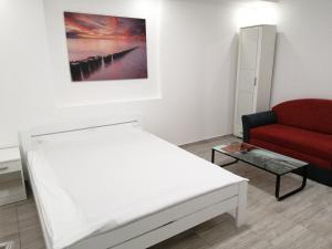 a bedroom with a white bed and a red couch at Airport view Apartment in Belgrade