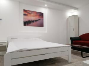 a white bedroom with a bed and a red couch at Airport view Apartment in Belgrade
