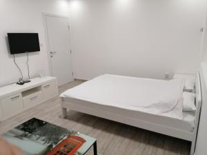 a white bedroom with a bed and a tv at Airport view Apartment in Belgrade