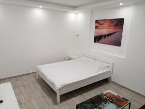 a bed in a white room with a picture on the wall at Airport view Apartment in Belgrade