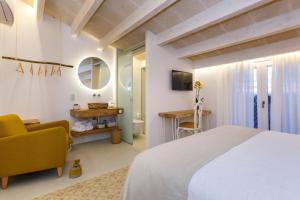 een slaapkamer met een bed, een bureau en een stoel bij Hotel S'Estil-let in Es Migjorn Gran