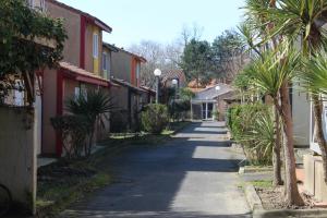 una calle vacía con palmeras y casas en MAISON les ARCADES, en Soustons