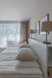 a white bedroom with two beds and a window at Sun City Apartment in Šiauliai