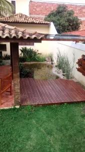 eine Holzterrasse mit einer Bank im Hof in der Unterkunft Casa piscina, mar e lagoa in Araruama