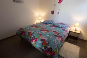 - une chambre dotée d'un lit avec un couvre-lit floral dans l'établissement Chez Emilie & Charles Classé 4 étoiles, à Hunawihr