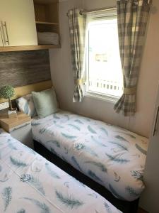Duas camas num pequeno quarto com uma janela em 3 bed presitage caravan Doniford Bay em Watchet
