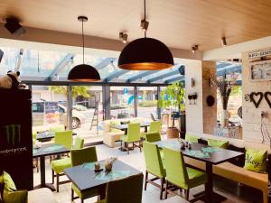 a restaurant with green chairs and tables and windows at Apartman Rubin in Sárvár