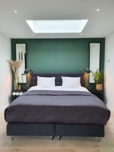 a bedroom with a large bed and a green wall at Studio Smidt in Den Burg