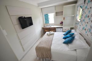 a bedroom with a bed with blue pillows on it at Pousada Retiro das Ilhas in Bombinhas