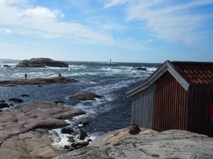 un edificio sentado en las rocas cerca del océano en Saltviks Stugby & Camping, en Grebbestad