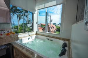a bath tub in a bathroom with a window at Pousada Retiro das Ilhas in Bombinhas