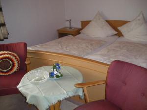 a bedroom with a bed and two chairs and a table at Pension Haus Ludwig in Schotten