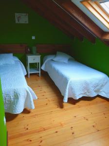 Habitación con 2 camas, paredes verdes y suelo de madera. en En busca del viento del norte en Santillana del Mar
