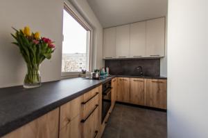 a kitchen with wooden cabinets and a vase of flowers at Słoneczna Apartamenty in Katowice