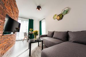 uma sala de estar com um sofá e uma parede de tijolos em Słoneczna Apartamenty em Katowice