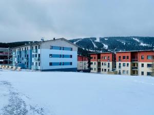 un grupo de edificios con nieve en primer plano en Luxury Keilberg Apartment, en Loucná pod Klínovcem