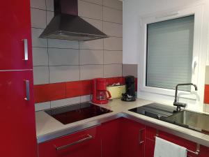 a small kitchen with red cabinets and a sink at 3 Vallées Appartement Mina in Les Menuires +34 photos