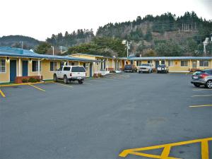 a parking lot with cars parked in front of a motel at Motel 101 in Gold Beach