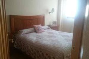 a bedroom with a bed with a pink pillow on it at Piso en Los corrales de buelna (Cantabría) in Los Corrales de Buelna