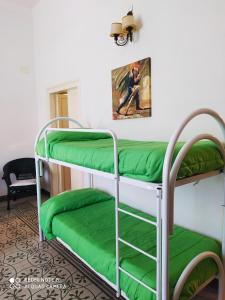 a room with two bunk beds with green sheets at Agli Antichi Quartieri Apartments in Alcamo