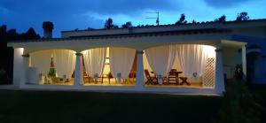 a house with white drapes and a table and chairs at B&B Briosa in Castiadas