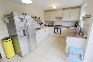 a kitchen with white cabinets and a refrigerator at EasyTravel Luxury NEC/Airport 3 beds House in Birmingham