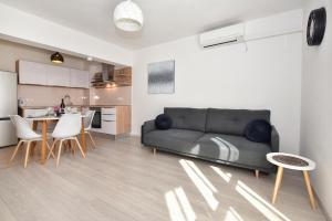 ein Wohnzimmer mit schwarzem Sofa und eine Küche in der Unterkunft Apartman Luka in Igrane