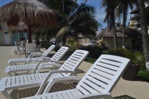 een groep witte ligstoelen op het strand bij Salvia Condominio in Cancun