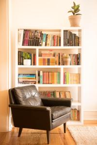 a leather chair in front of a book shelf with books at Flattered to be in Lisboa in Lisbon