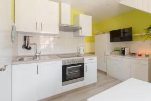 una cocina blanca con armarios blancos y fregadero en Apartments Green Paradise en Bohinj