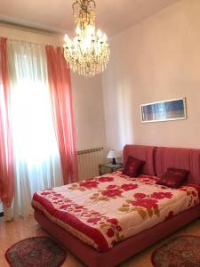 ラ・スペツィアにあるAppartamento Auroraのベッドルーム1室(赤いシーツとシャンデリア付きの大型ベッド1台付)