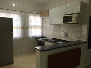 a kitchen with a stove and a microwave at Apartamento em Bertioga sp in Bertioga