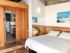 a bedroom with a white bed and a bathroom at Caloura 66 in Lagoa