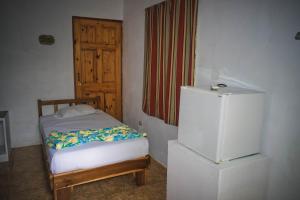 a small bedroom with a refrigerator and a door at Mapi's Cabins in Paquera