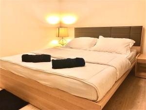 a large white bed with two black pillows on it at The 21 MuangthongThani in Pak Kret +19 photos