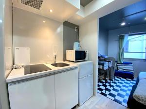uma pequena cozinha com um lavatório e um micro-ondas em Belle harmonie 102 em Tóquio