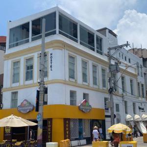 un edificio blanco y amarillo con gente delante de él en Manhatã Hostel, en Salvador